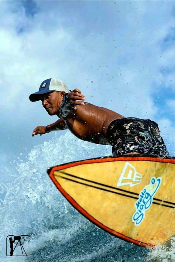 Surfeur en plein virage sur une planche orange à Siargao, des gerbes d'eau au rail
