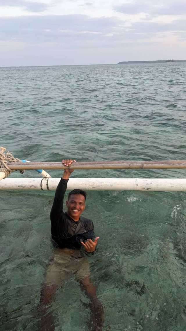 Un moniteur dans une eau transparente, accroché au balancier du bateau