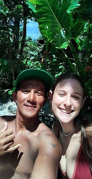 Un moniteur et un élève souriants en selfie devant de grandes feuilles vertes