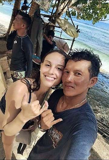 Un moniteur et un élève souriants, serrés dans un selfie au bord de la mer, avec shaka