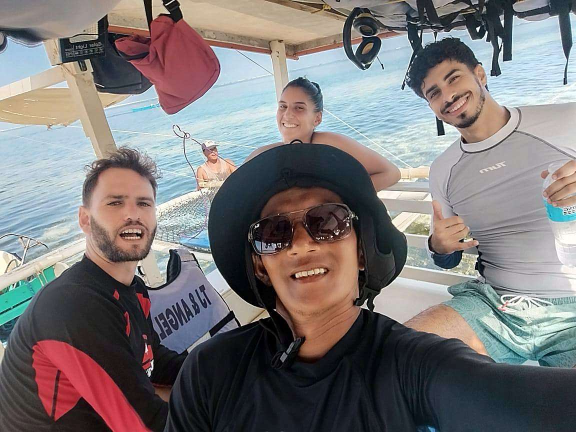 Un moniteur de Surfing Sirago fait un selfie avec des élèves sur le bateau