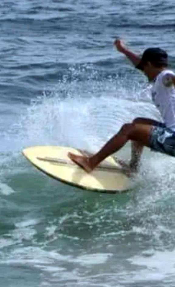 Surfeur en virage sur une planche crème, avec des éclaboussures à l'arrière