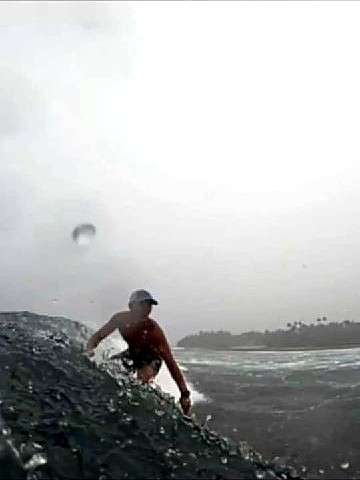 Un surfeur sur une vague sous un ciel gris et pluvieux