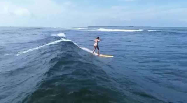 Un surfeur prend une vague du large, la côte de Siargao en arrière-plan