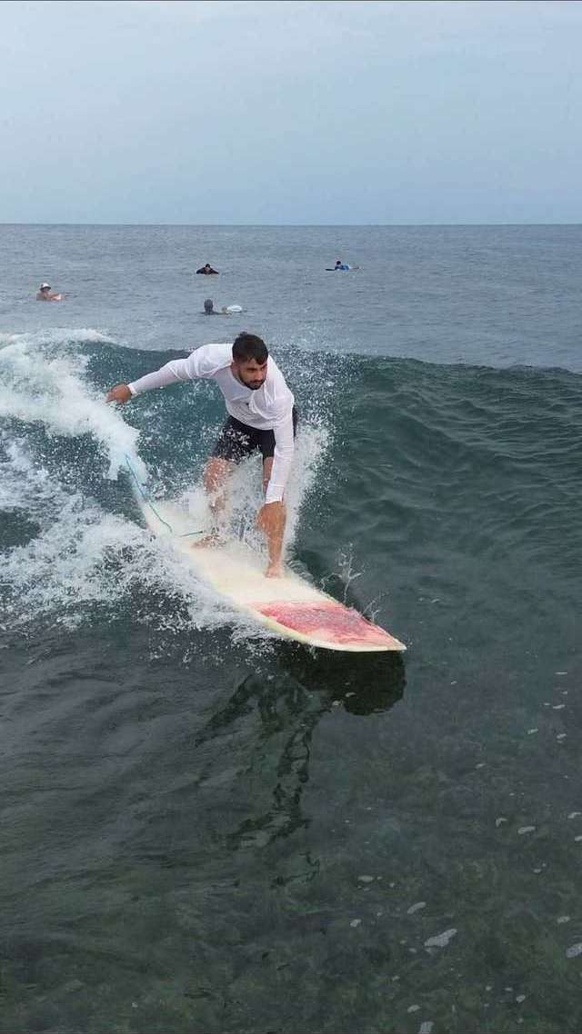 Un surfeur en lycra blanc fait un virage sur la vague