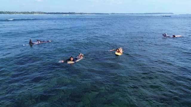 Des surfeurs rament au-dessus du récif dans une eau claire