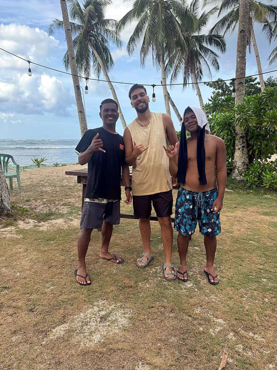 Trois surfeurs sous les palmiers, au bord de la mer