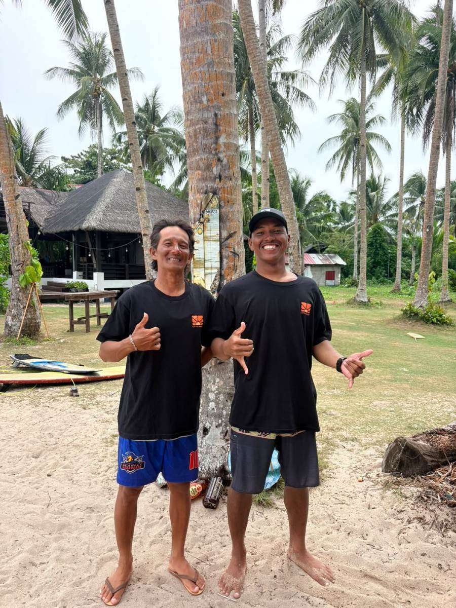 Deux moniteurs de Surfing Sirago sur le sable, sous les cocotiers